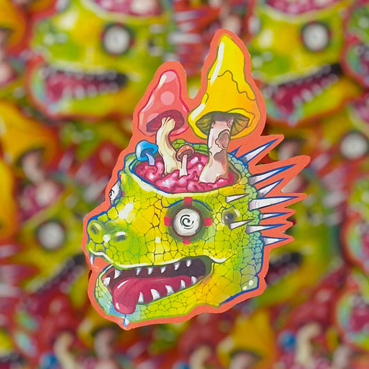 A colorful sticker or decal featuring a cartoon monster head with mushrooms growing out of its head, shown in sharp focus against a blurred repeating background of the same design.